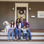 Family takes a portrait together on the front porch of their home
