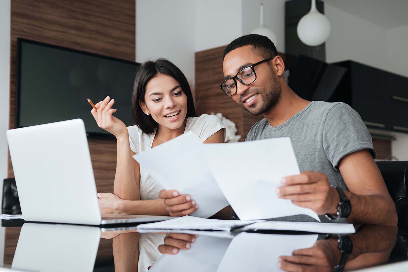 Cheerful loving young couple using laptop and analyzing finances