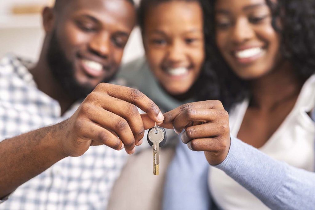 Family with young daughter holding keys from their new home, selective focus on hands, closeup.